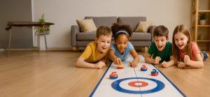 Grupo de niños disfrutando de una partida de curling de mesa sobre el suelo de un salón